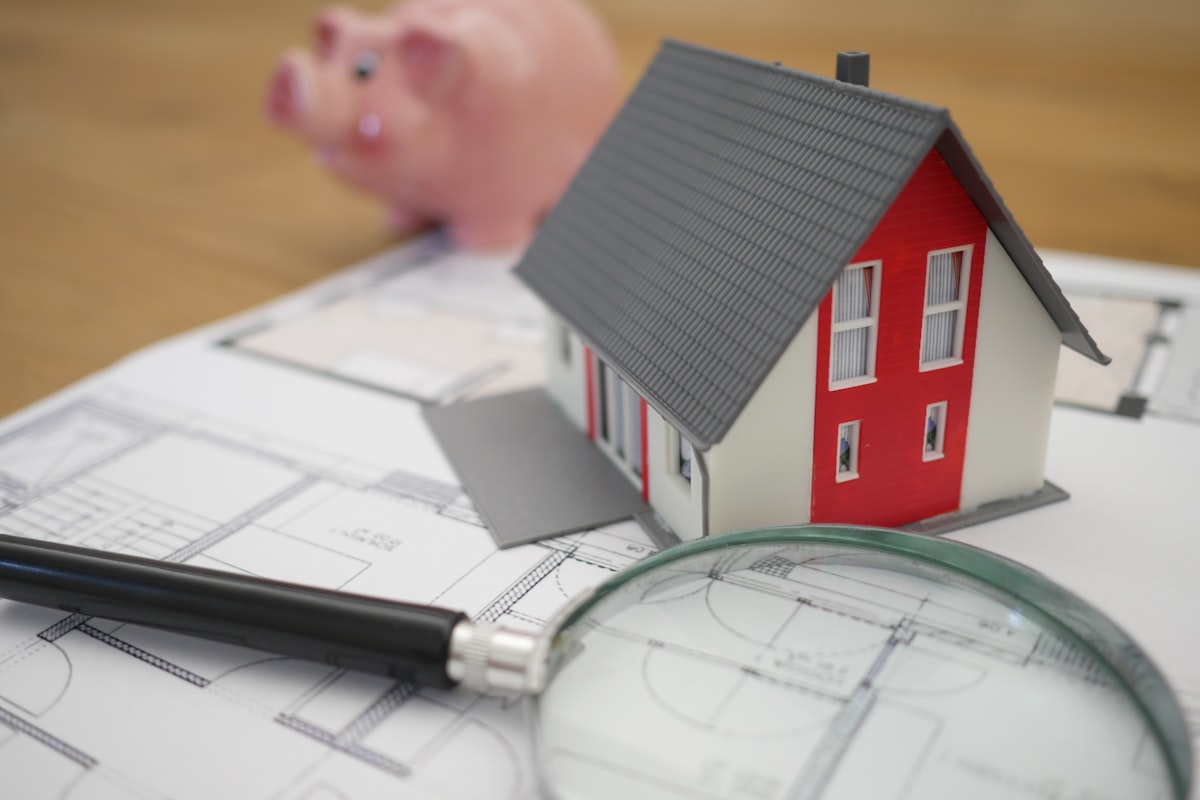Model house on property plans with magnifying glass